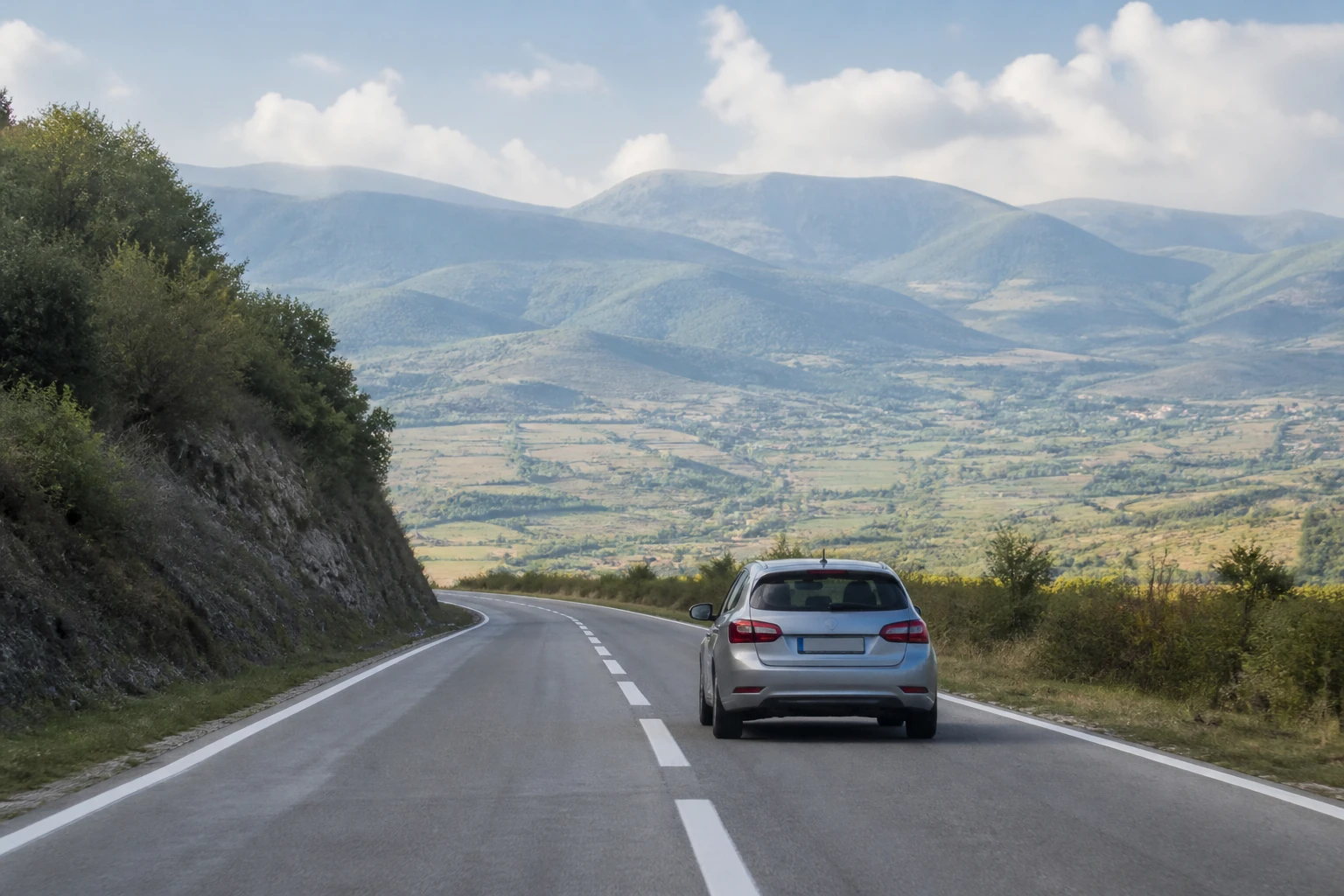 Rental car on a mountain road through a Bosnian river valley