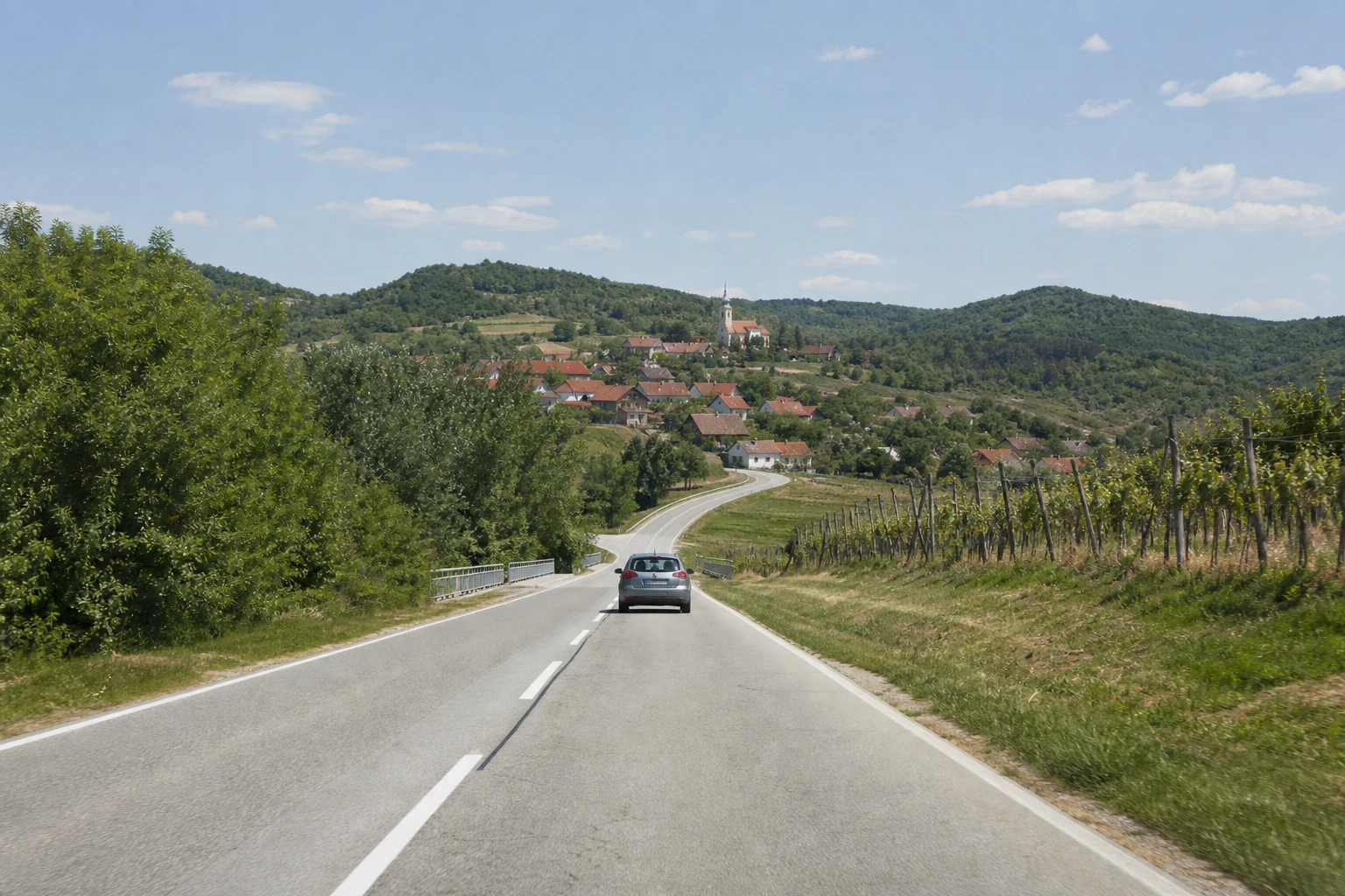 Rental car on a road through inland Croatia hills and villages