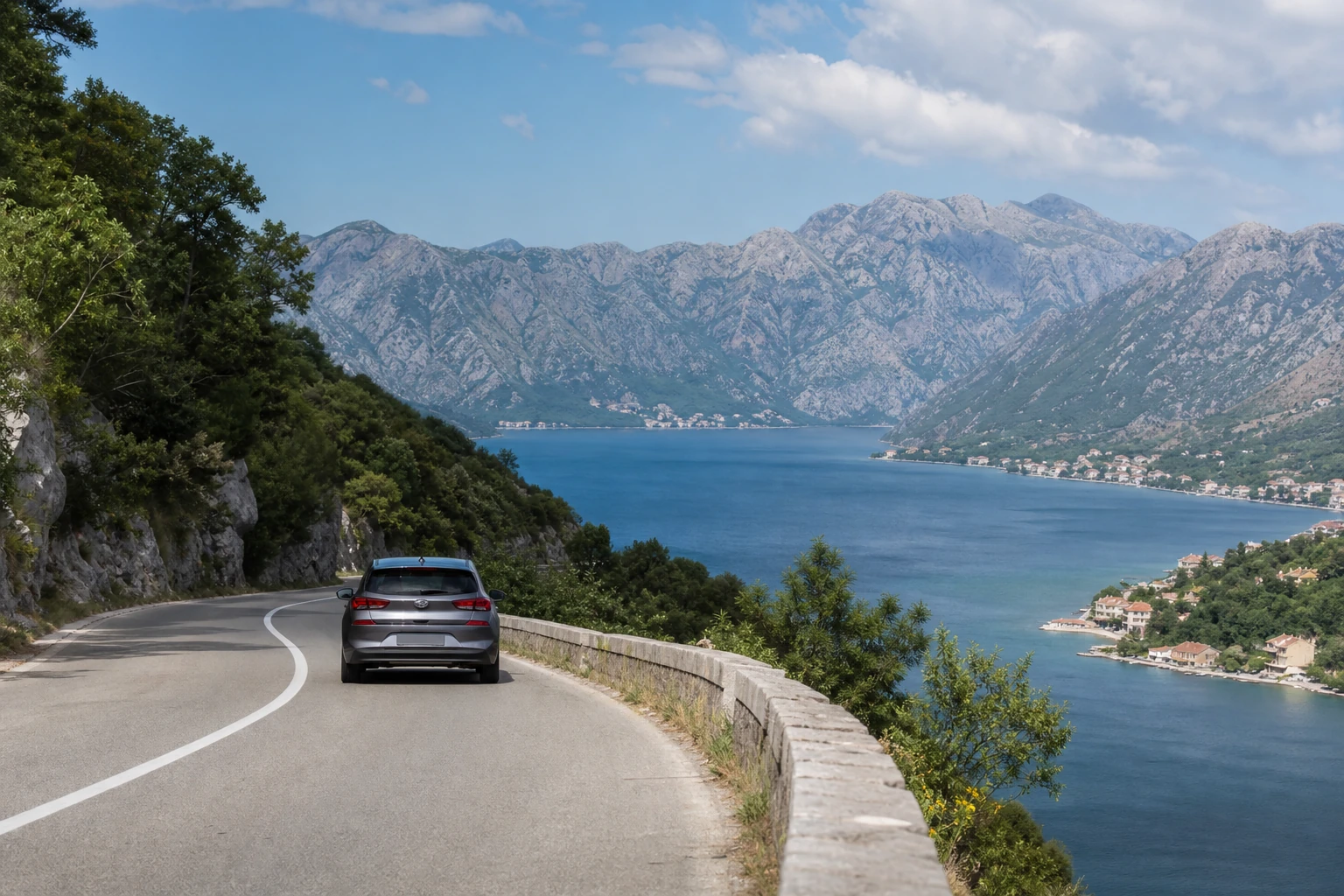 Rental car on a coastal road beside the Bay of Kotor in Montenegro