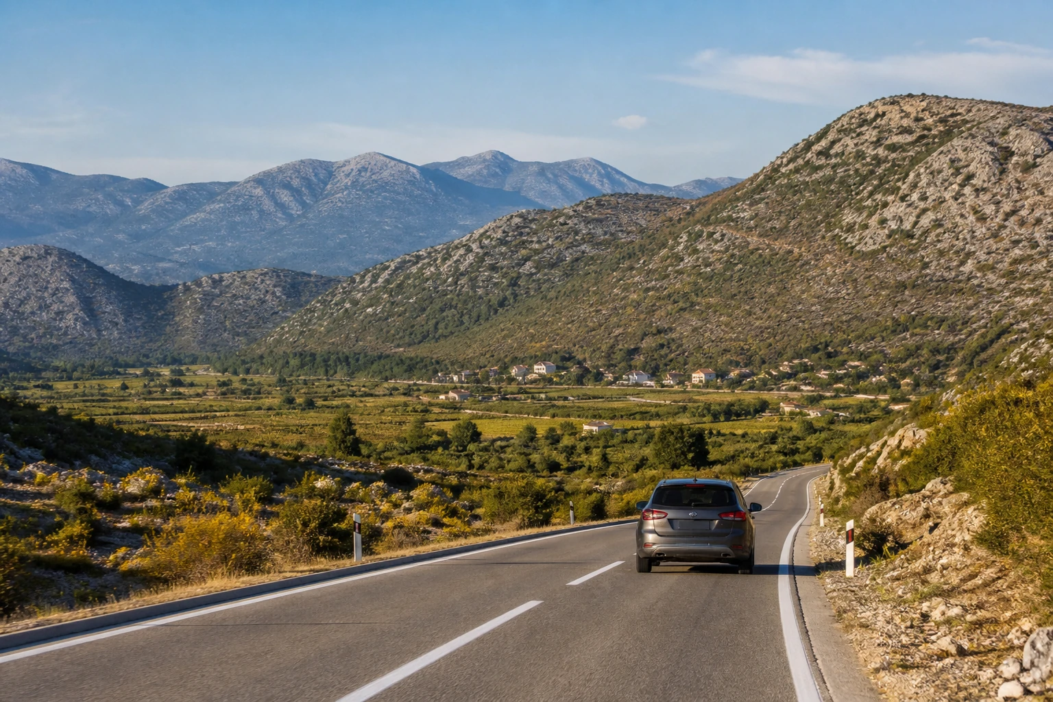 Rental car on a road through Montenegro's inland karst valley