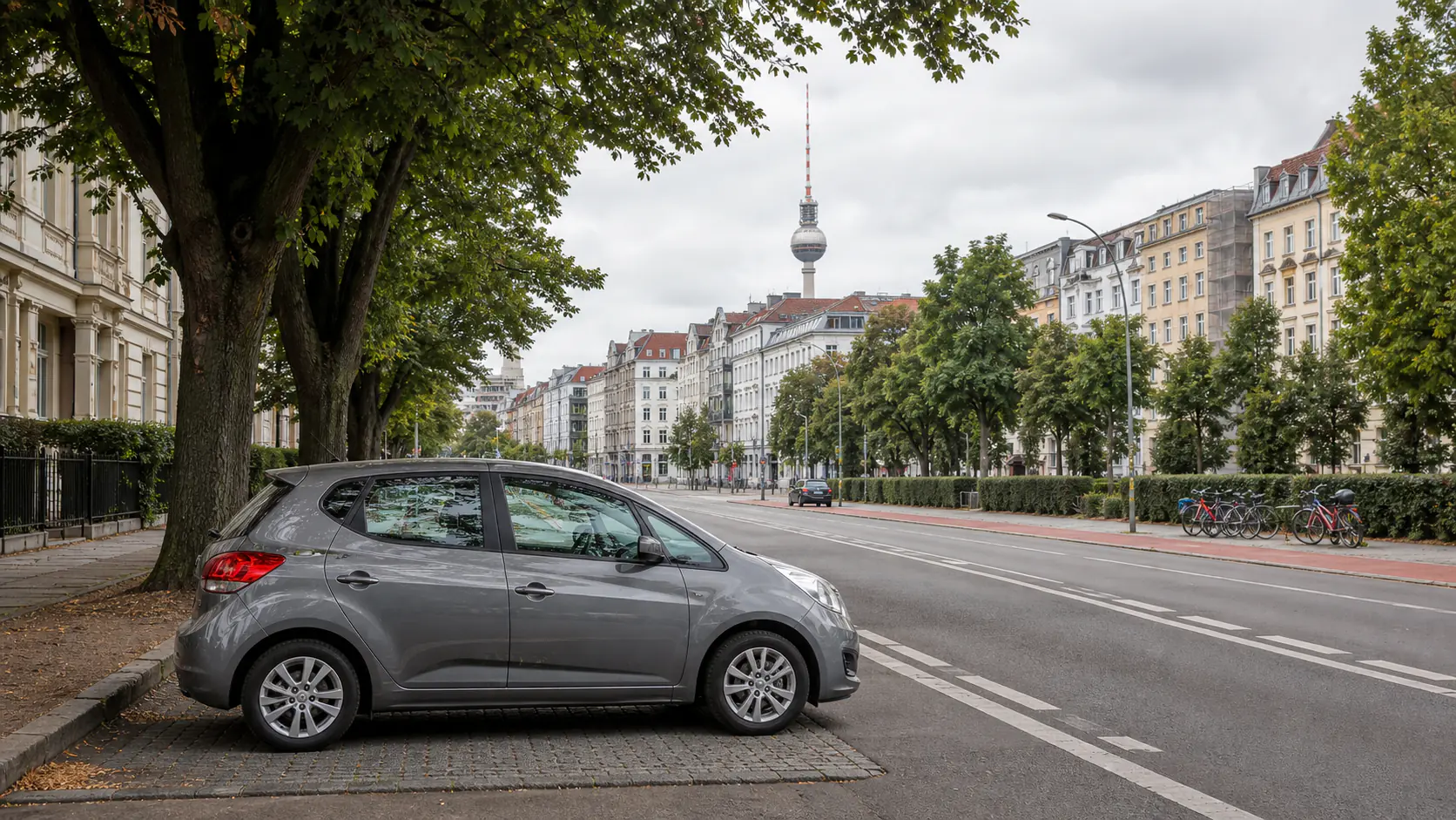 Illustrative rental car beside a tree-lined city street with a television tower in the distance