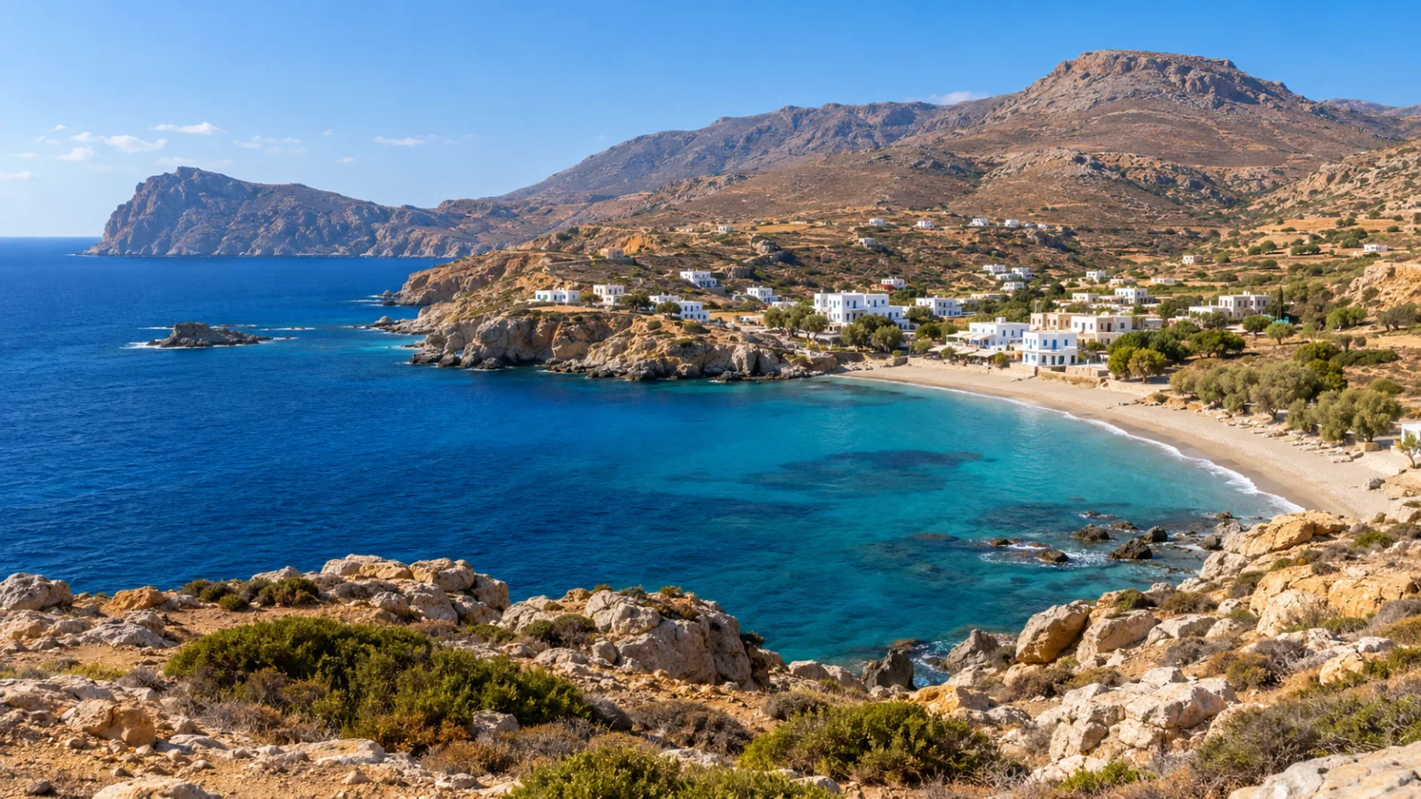 White coastal houses below rugged ochre mountain slopes