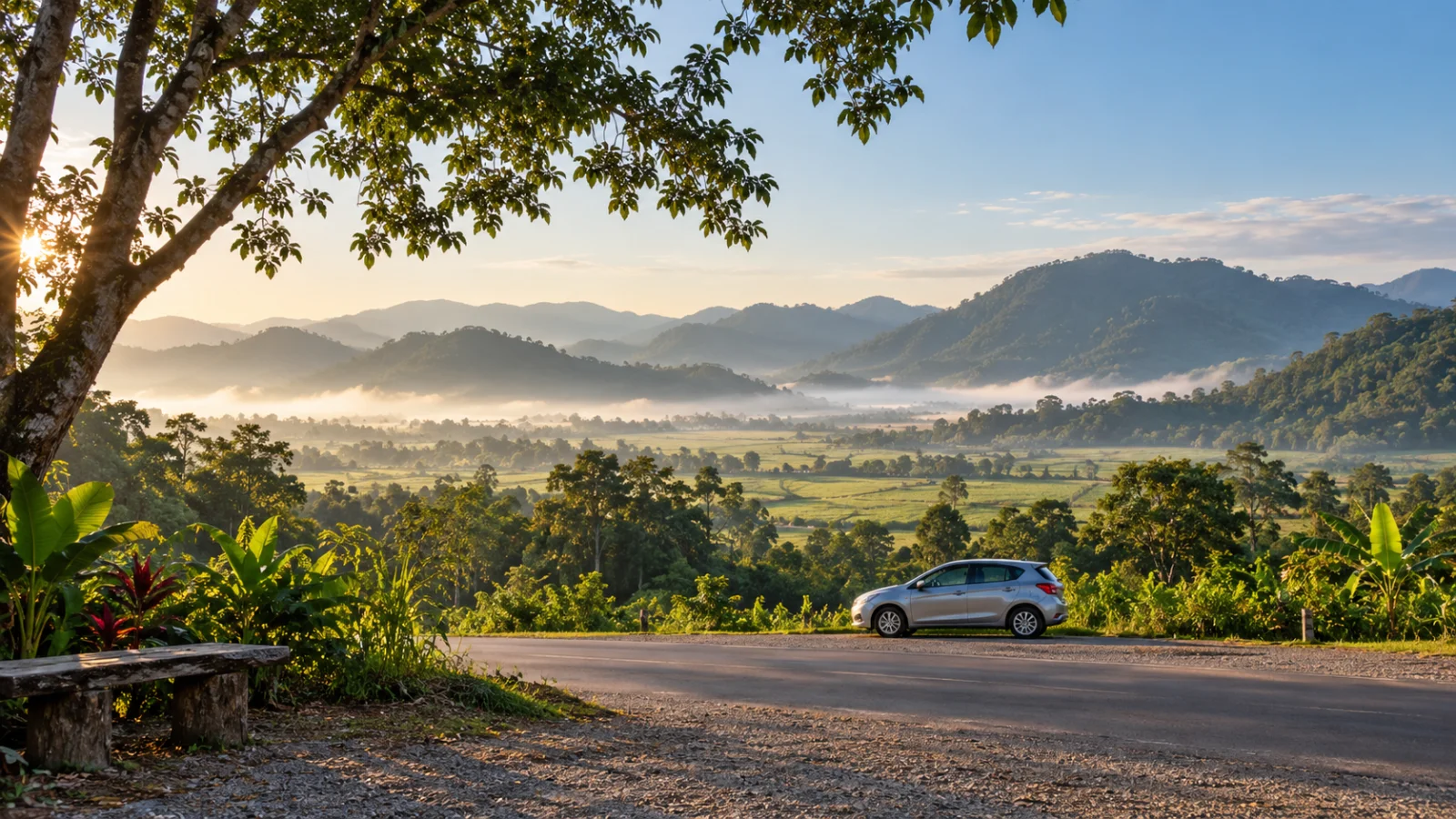 Tree-framed green valley with a small silver car parked beside the road