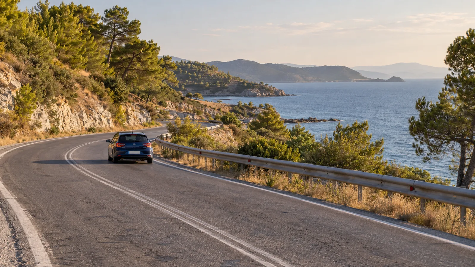 Blue compact car on a paved coastal road with pine trees and sea views